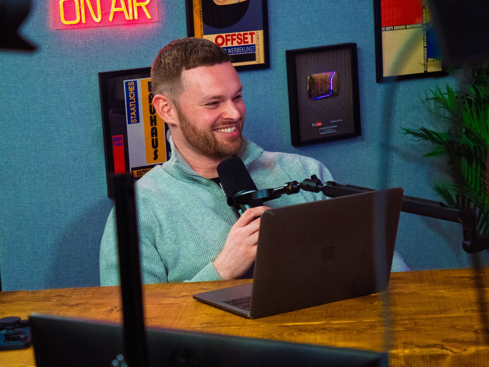 James Hacking recording in his podcast studio under an On Air neon sign